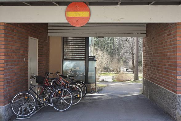 A photo of an entrance to a courtyard on a sunny spring day. There are bicycles on the left and a person in the distance.