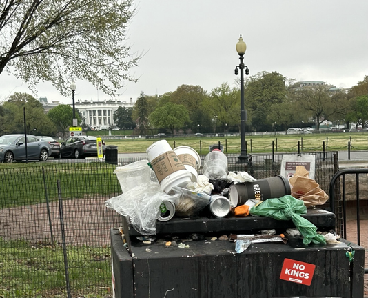 In front of the White House, a garbage can symbolically is overflowing with garbage.
