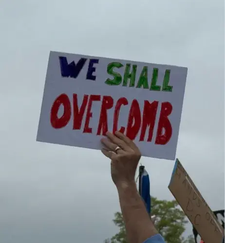 A protest sign that reads, "We shall overcomb."