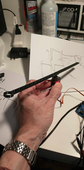 An image showing the sam 3D printed arm now connected to the Servo Motor, a small rectangular shaped box under the arm about half way down the arm. This was the Mark 1 prototype with the servo motor mounted in the middle of the arm. Subsequent tests would show that the length of the arm prevented the servo from moving it fast enough to give a good pseudo representation of a seismograph.