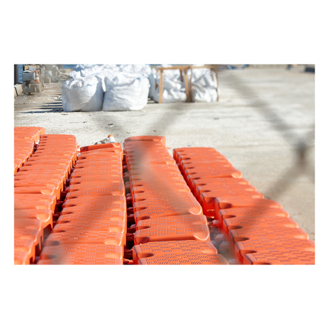 looking through a chainlink fence to bright orange plastic fencing in rows on a dock.