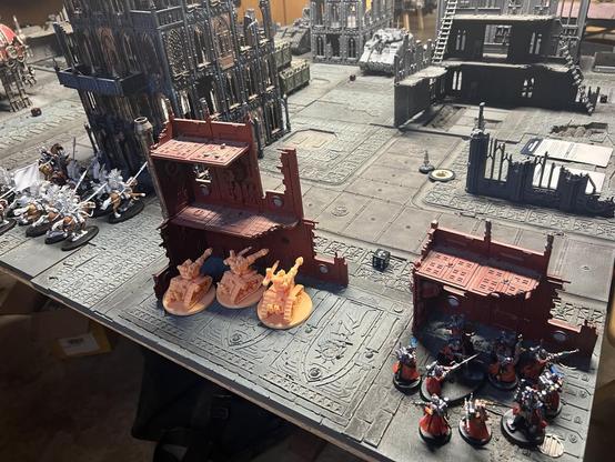 Warhammer 40K battlefield 

Deathriders, Kataphrans, and Skitari Rangers lurking behind buildings in foreground. Space marine hover tank in distance.