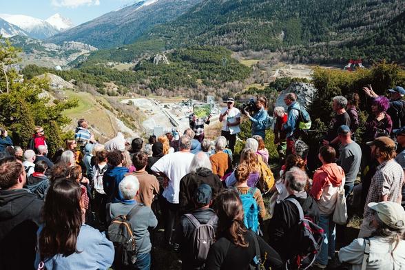 Vue de la visite : le groupe est face à un site des travaux, un militant leur montre une photo du lieu avant le saccage...