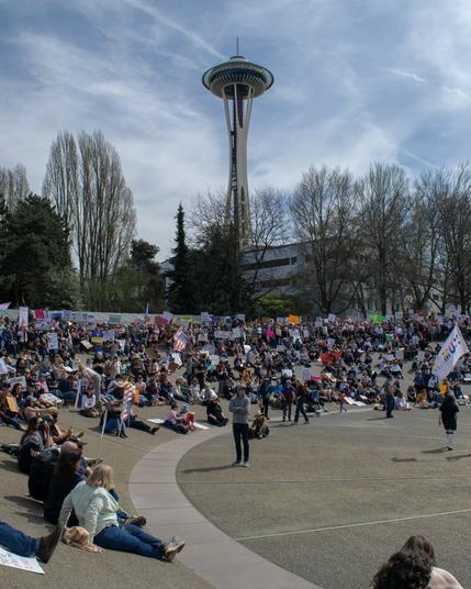 Ralliers gathered within the International Fountain at Seattle Center, finding seating on the sloped walls.