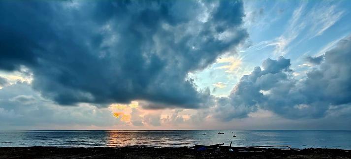 Rising sun rays scattered amidst the cloudy skies at the Marina Beach. Also in the frame are several fishing boats.