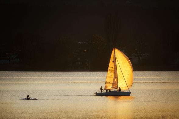 Ein Segelboot und ein Skiff im Abendlicht.