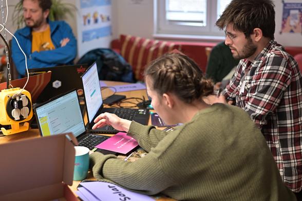 Auf dem Bild sind zwei Personen zu sehen, die sich je über einen Laptop beugen. Auf den Laptopbildschirmen sind Ausschnitte des Escape Games zu sehen.