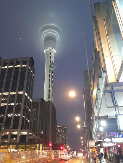 En plein centre d'Auckland se dresse la Skytower. L'ambiance est brumeuse, c'est le soir, une pluie fine tombe. La tour à la tête dans les nuages, au sol les néo-zélandais marchent sereinement, éclairés par les lumières de la ville.