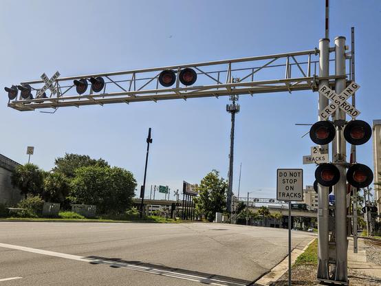 Crossing lights and railroad tracks passing over the pavement of a street.