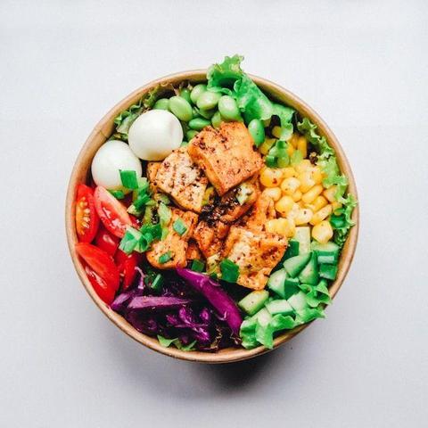 Image shows bowl full of colourful, healthy food - including two peeled, boiled eggs, tomatoes, green beans, sweet corn, cucumber, red cabbage and more. The image is freely available thanks to Anh Nguyen on Unsplash