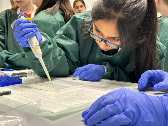A girl in a lab coat learns how to use a pipette.