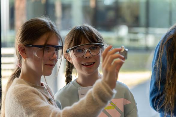 Two girls wearing safety goggles admire aluminum cast in the shape of a star.