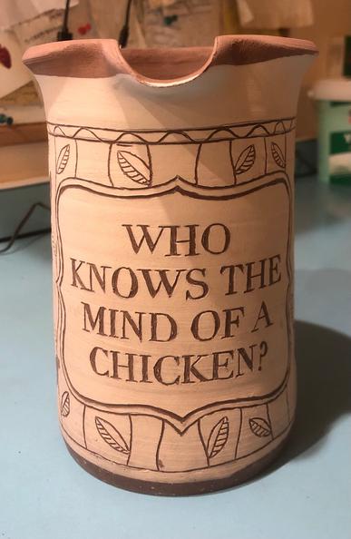 Photo of an unfired clay jug decorated using the sgraffito technique with chicken and plant motifs.