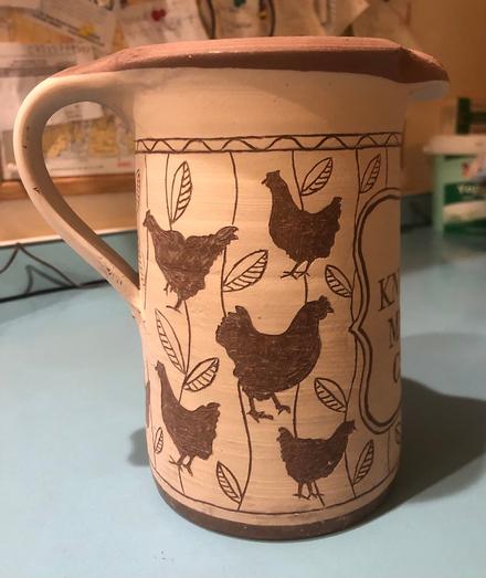 Photo of an unfired clay jug decorated using the sgraffito technique with chicken and plant motifs. right side.