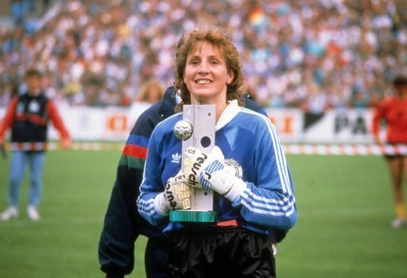 Marion Isbert hält lächelnd die Trophäe der EM 1989 in beiden Händen, die noch in ihren Torhandschuhen stecken.