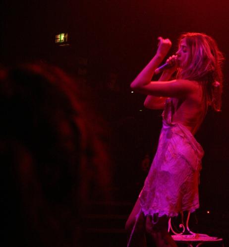 Female performer onstage under red stage lights.