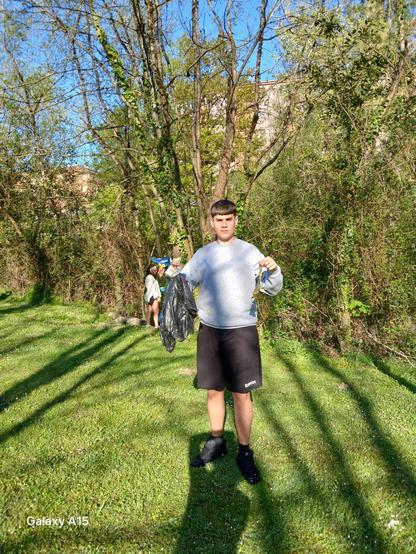 Gazte bat errekondoan batutako zaborra erakusten