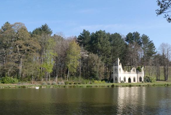 A decorative 'ruined abbey' built alongside the serpentine man made lake at Painshill Park, a restored C18 landscaped garden at Cobham, Surrey, England. April 2025.