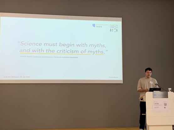Münker in front of a slide with a big quote about “criticism of myths”