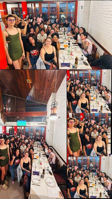 A group of people attending WNB.rb Tropical on Rails dinner. There is a long white table with dinnerware in a white brick restaurant, filled with happy, smiling faces of many community members.