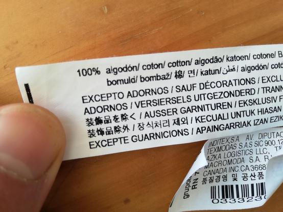 Etiqueta de ropa. Dice 100% algodón, excepto adornos.