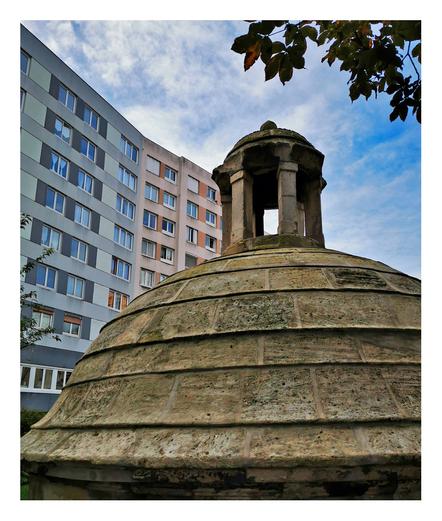 rue Compans
cette coupole semble correspondre à un ancien puits ou réservoir d’époque, intégré dans un jardin urbain, très probablement dans l’ancien domaine du Château de Bellevue situé au 62 rue Compans.
Ce type de construction en pierre taillée avec coupole et lanterneau est typique des puits maçonnés ou réservoirs d'eau que l’on trouvait dans les jardins de propriétés bourgeoises ou nobles au XIXe siècle. Le bâtiment moderne en arrière-plan montre bien la juxtaposition entre l’ancien et le nouveau, caractéristique du 19e arrondissement.
Il y a de fortes chances que cette structure fasse partie des vestiges du jardin du Château de Bellevue, devenu une copropriété et qui conserve quelques éléments historiques dans ses espaces verts.