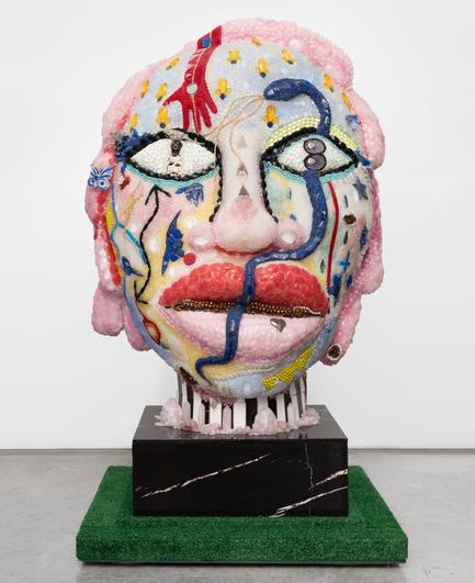 a large mixed-media sculpture of a head coated with beads and other materials
