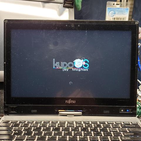Photo of my Tablet PC Thingie on boot. The normal Fujitsu logo has been replaced by a colorful custom "kupo O S" logo. The normally black text has a stark white outline to allow it to be read on the standard black background of the boot screen. The modern Microsoft Windows loading animation is seen underneath it.