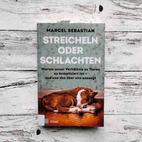 Auf dem Foto ist das Buch "Streicheln oder Schlachten" von Marcel Sebastian auf einer hellen, holzähnlichen Fläche abgebildet.