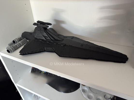 The venator class republic star destroyer model has been painted black and sitting on a white shelf.