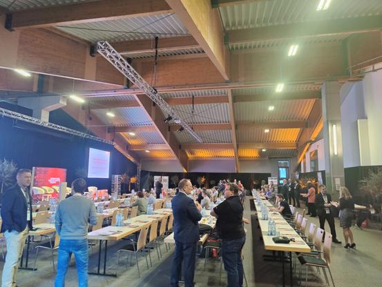 Conference hall with tables and the stage on the left side. Wooden beams and metal roof