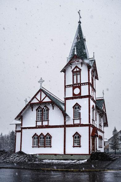 Húsavík’s red-and-white wooden church framed by falling snow during a winter storm in northern Iceland.