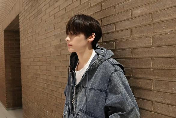 Kai backstage in Barcelona, wearing denim, posing in front of a brickwall