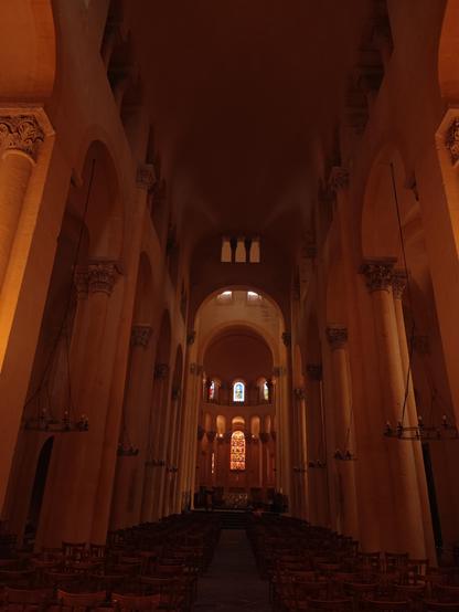 Intérieur d'une église romane dépouillée, vue sur le vaisseau central dans les tons orangés
