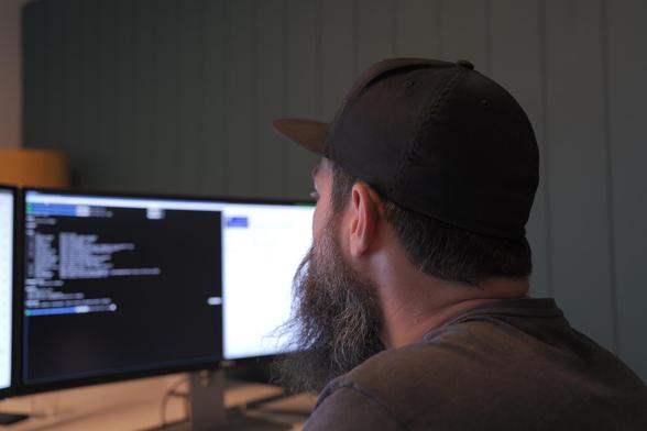 Mann vor Computerbildschirm, auf dem Bildschirm ein offenes Terminal mit Code.