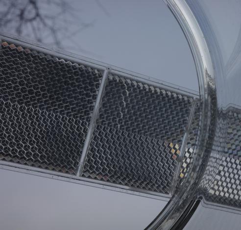 The dark side of a reflector doing its job. The transparent reflector was placed on a glass cylinder without bases and photographed from below against the sky. The sun's rays are almost completely reflected and partially refracted, causing some parts of the reflector to appear colorful. The cylinder also refracts some light.
