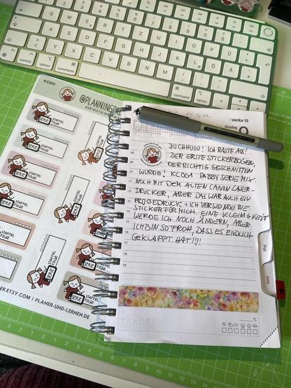 Tastatur, Stickersheet Nd Journal auf grüner Schneidematte. Der Text in meinem Journal (automatisch aus dem Bild erkannt): JUCHHUUU! ICH RASTE AUS! DER ERSTE STICKERBOGEN, DERRICHTIG GESCHNITTEN WURDE. KCOO1 PABBY SERIE MIX. NOCH MIT DEM ALTEN CANON LASER - DRUCKER, ABER DAS WAR AUCIt EI PROBEDRUCK + ICH VERWENDE DIE STICKER FÜR MICH. EINE KLEIMGKEiT WERDE ICH NOCH ÄNDERN, ABER ICHBIN SO FROH 1, DASS ES ENDLICH GeKLAPPT. HAT!!!
