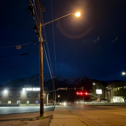 A long exposure shot looking eastward down a street before dawn. A streetlight is in the foreground and an H&R Block is on the corner of the intersection behind it.