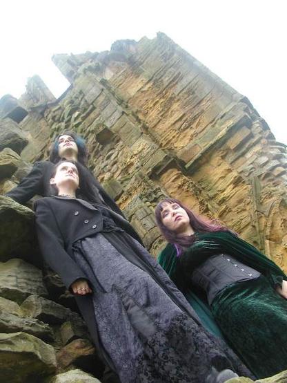 Three young people standing in formation at the ruins of the Abbey at Whitby.