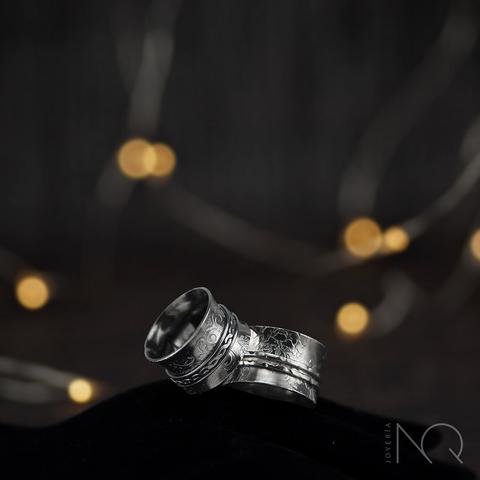 Foto de 2 anillos anchos de tipo spinner con grabados ornamentales  bañados en rutenio que les da un tono de metal gris oscuro