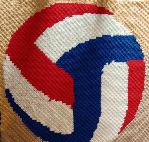 Crocheted afghan using the corner to corner method so it looks like a red, white, and blue volleyball.