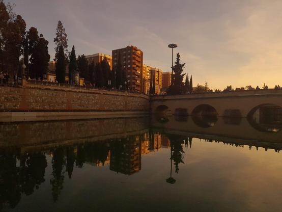 Vista del río Genil al atardecer bajo un puente.