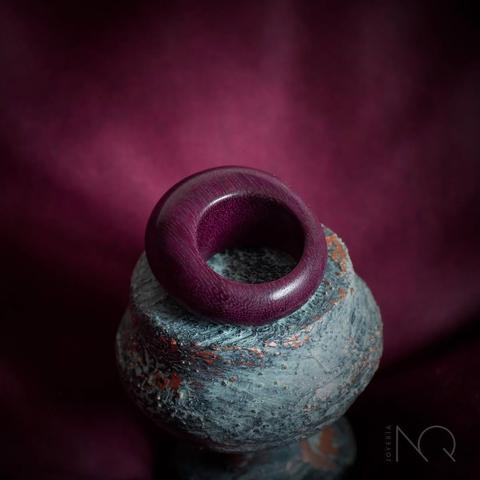 un anillo de formas redondas de madera pulido hasta brillar y de color morado profundo