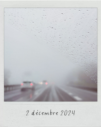 l'autoroute dans le brouillard et sous la pluie à travers un pare-brise sur lequel on voit les gouttes de pluie