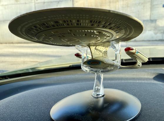 A model of the Starship Enterprise mounted on a dashboard, showcasing the iconic saucer section and nacelles, with a clear display stand.