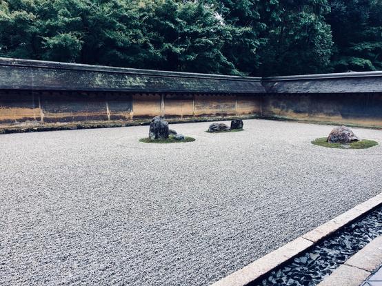 Sideview of the rock garden of Ryōan-ji. Among the straight lines of the small rocks, some “islands” of bigger rocks can be seen.