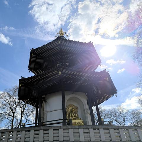 A pagoda with a golden Buddha statue at the bottom. The entire structure is on a raised base which has stairs leading up to it. There's 4 Buddha statues on each side of the pagoda, each representing a time of his life.