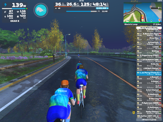 Screenshot from Zwift of cyclists avatars riding at night in Team Velos attire