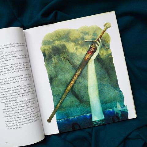 The right page of a book showing an illustration of a white arm coming out of water and holding a sword.