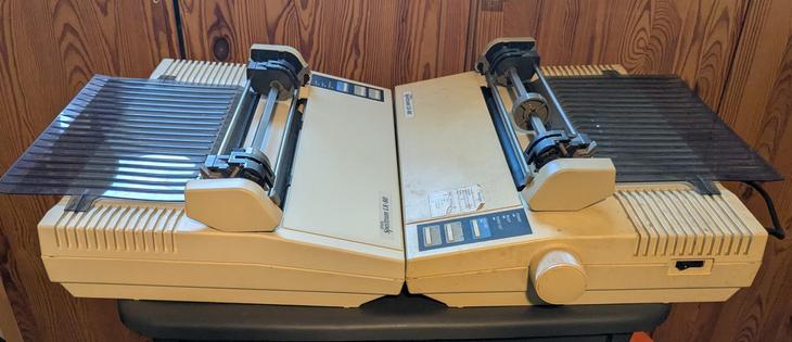 Two identical mid 1980s dot matrix printers, the one on the right being far, far dirtier than the one on the left.